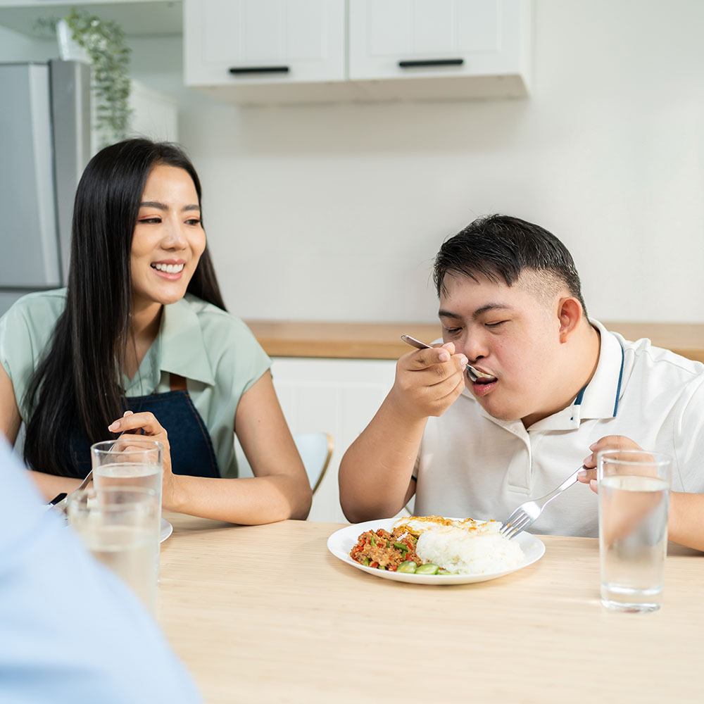 Young female caregiver watching male patient eating